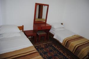two beds in a room with a mirror and a dresser at Hotel Hisarlık in Halileli