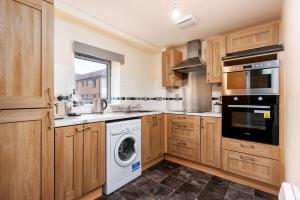 a kitchen with wooden cabinets and a washer and dryer at Cosy Apartment & Central Location & Contractors & DSA in Doncaster