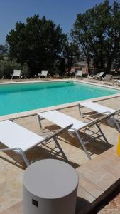 a swimming pool with white lounge chairs and a table at Agriturismo Pane e Olio in Todi