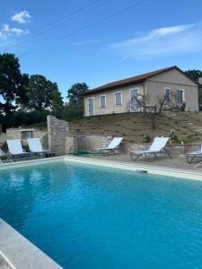 a swimming pool with chairs and a house in the background at Agriturismo Pane e Olio in Todi