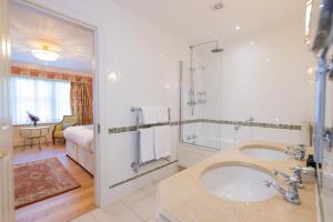 a bathroom with a tub and a shower and a sink at The Dixcart Hotel in Sark