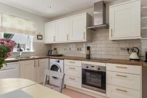 a kitchen with white cabinets and a dishwasher at Parsonage Cottage- Peaceful, Dog Friendly Cottage in Begelly