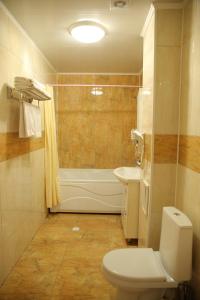 a bathroom with a toilet and a tub and a sink at Sweet Home Hotel in Atyraū