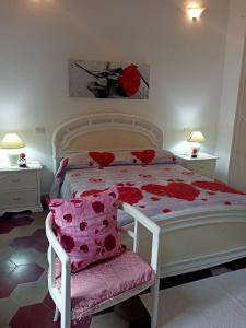 a bedroom with a white bed with red flowers on it at Appartamento vacanze Le rose in Bosa