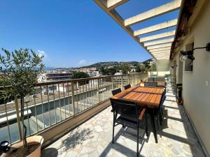 balkon z drewnianym stołem i widokiem na miasto w obiekcie RoofTop Apartement - Quartier Croisette - Esc'Appart w Cannes