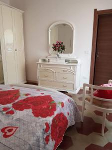 ein Schlafzimmer mit einem Bett und eine Kommode mit einem Spiegel in der Unterkunft Appartamento vacanze Le rose in Bosa