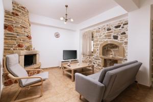 a living room with a stone wall and two chairs and a tv at Halkidio House in Sívas