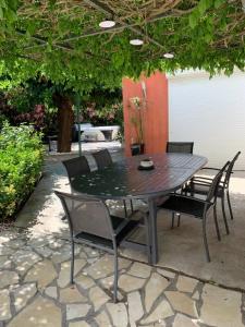 - une table et des chaises noires sur la terrasse dans l'établissement Les dahlias appartement 4 personnes Jacuzzi Barbecue Jardin arboré Climatisé, à Agde