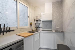uma cozinha branca com um lavatório e uma janela em logement cosy et moderne proche de toute commodité em Paris