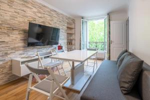 uma sala de estar com uma mesa e cadeiras e uma parede de tijolos em logement cosy et moderne proche de toute commodité em Paris