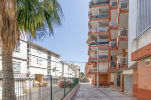 un edificio de apartamentos con una palmera y una pasarela en Apartamento Cerdeña Arysal, en Salou