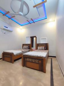 two beds in a room with a ceiling at Lavish Inn Islamabad in Islamabad