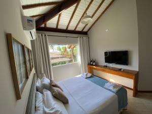 a bedroom with a bed and a tv and a window at KORA MAR - Taipu de Fora - BA in Barra Grande