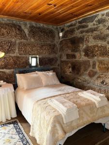 a bedroom with a bed in a stone wall at CASA DE CAMPO BENFEITO in Campo Benfeito +78 photos