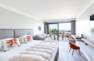 a white bedroom with a large bed and a couch at RESIDENCE SANTA MARIA in LʼÎle-Rousse