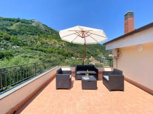 un patio con 2 sillas y una sombrilla en el balcón en Arya's House, en Colli di Fontanelle
