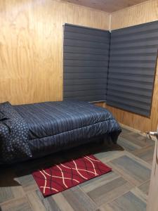 ein schwarzes Bett in einem Zimmer mit einer Holzwand in der Unterkunft Cabaña Recinto Valle Las Trancas in Recinto