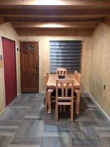 einen Holztisch und Stühle in einem Zimmer mit Tür in der Unterkunft Cabaña Recinto Valle Las Trancas in Recinto