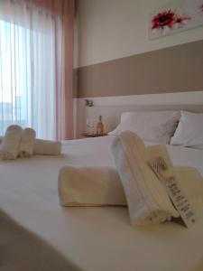 una camera da letto con un letto bianco e asciugamani di Hotel Baia Verde Gallipoli a Gallipoli