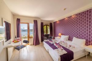 una camera d'albergo con un grande letto con carta da parati viola di Riva Bodrum Resort- Adult Only +16 a Gümbet Altre 71 foto