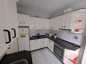 una cocina con armarios blancos y encimeras negras en Casa céntrica. A Coruña a 200m de la playa Riazor, en A Coruña