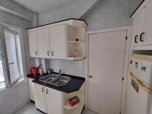 a small kitchen with a sink and white cabinets at Casa céntrica. A Coruña a 200m de la playa Riazor in A Coruña