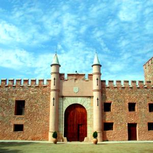 a large brick building with a gate and a door at Masía de San Juan Casas Rurales con piscina, aire acondicionado y vistas a la montaña in Segorbe