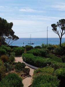 einen Garten mit einem Segelboot im Wasser in der Unterkunft Horizon d'Azur in Fréjus