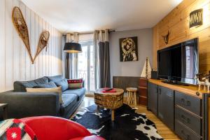 a living room with a couch and a tv at APPARTEMENT CENTRE VILLE PARKING COUVERT WIFI BALCON in Cauterets