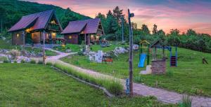a log cabin in a field with a playground at Holiday Park Plitvice Paradise in Korenica