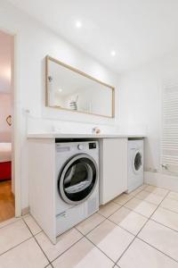 uma lavandaria branca com máquina de lavar e secar roupa em Les 4 horizons au sein d' une résidence calme em Talant