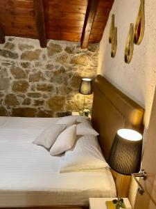 a bedroom with a bed and a stone wall at STONEHOUSE & CASA AL SOLE e AL MARE in Nea Roda +65 photos