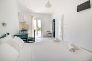a white bedroom with a bed and a table at Ikaros Studios & Apartments in Naxos Chora