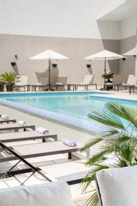 a pool with lounge chairs and umbrellas in a hotel at Hotel Cvita in Split