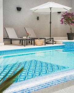 a swimming pool with two laptops on a table and an umbrella at Hotel Cvita in Split