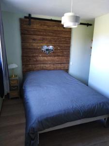 a bedroom with a blue bed with a wooden headboard at Au petit gravelot 