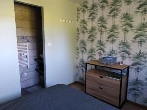 a bedroom with a bed and a wall with a palm tree wallpaper at Au petit gravelot in Aulx-lès-Cromary