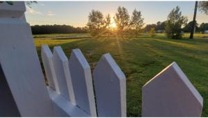 Ein weißer Zaun auf einem Feld mit Sonnenuntergang im Hintergrund in der Unterkunft Legacy Lodge Bunkhouse in Windsor