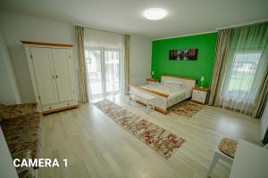 バマにあるPensiunea ARC Bucovinaの緑の壁のベッドルーム1室、ベッド1台が備わります。