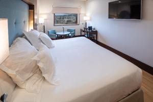 a hotel room with a large white bed with pillows at Barceló Granada Congress in Granada