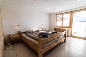 1 dormitorio con cama de madera y ventana grande en Haus Derby, Riederalp West, en Riederalp