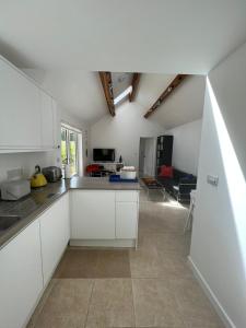 a kitchen with white cabinets and a living room at The Cottage at No. 3 in West Lavington