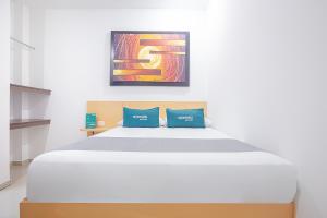 a bedroom with a large white bed with blue pillows at Ayenda Alameda Real in Montería