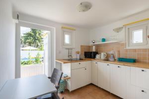 a kitchen with white cabinets and a table and a window at VirágLak in Gárdony