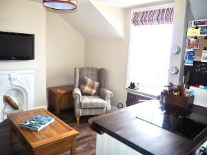 a living room with a chair a table and a tv at The Seaview Snug in Whitstable
