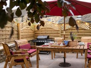 un patio con mesa, sillas y parrilla en Woodview Farm en Huddersfield
