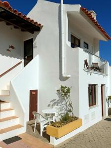 a white house with a table and chairs at Casa dos Pinheiros in Praia da Arrifana