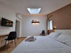 a bedroom with a large white bed and two chairs at Rifugio Baita Motti in Domodossola