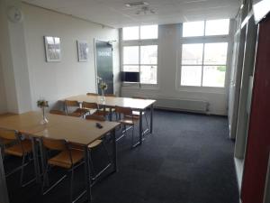 une salle de conférence avec des tables, des chaises et des fenêtres dans l'établissement Pension Zevenbergen, à Zevenbergen