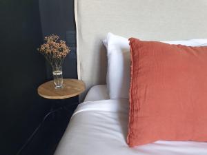 een bed met een rood kussen en een vaas met bloemen op een tafel bij Sojolidays - Appartements d'hôtes & Brocante in Rorschwihr
